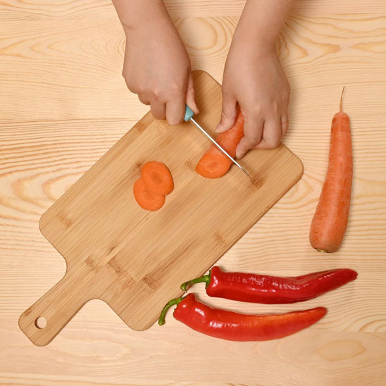 planche-a-decouper-bois-personne-qui-coupe-des-carotte-et-piment