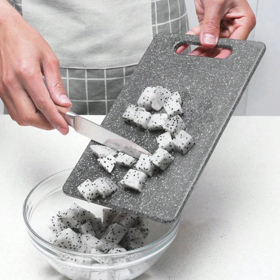 planche-a-decouper-personne-qui-transfert-des-fruits-couper-dans-un-bol-en-verre