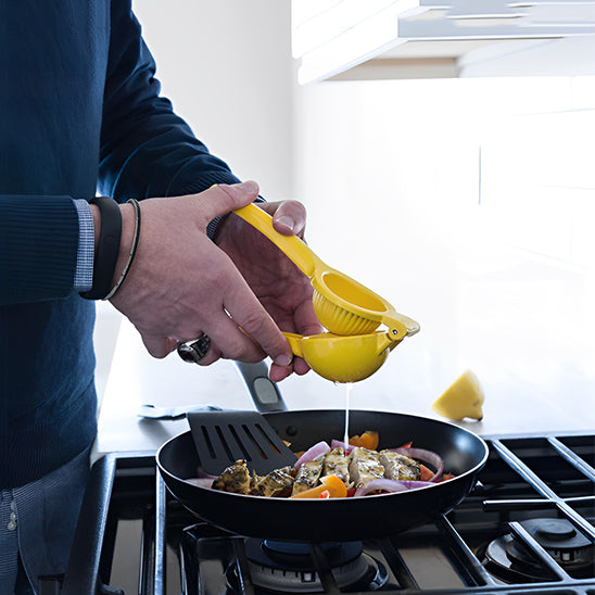 presse-agrume-personne-qui-presse-un-citron-dans-une-poele-avec-un-poisson