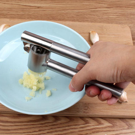 presse-ail-personne-qui-ecrasse-une-ail-dans-une-assiette-bleu