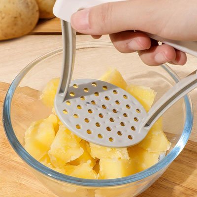presse-puree-personne-qui-ecrase-des-patate-dans-un-bol-en-verre